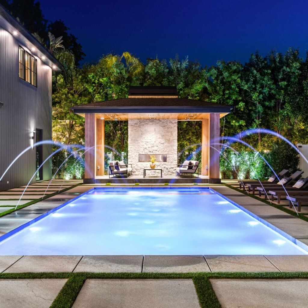 Luxurious modern backyard with illuminated swimming pool at night. in Fredericksburg