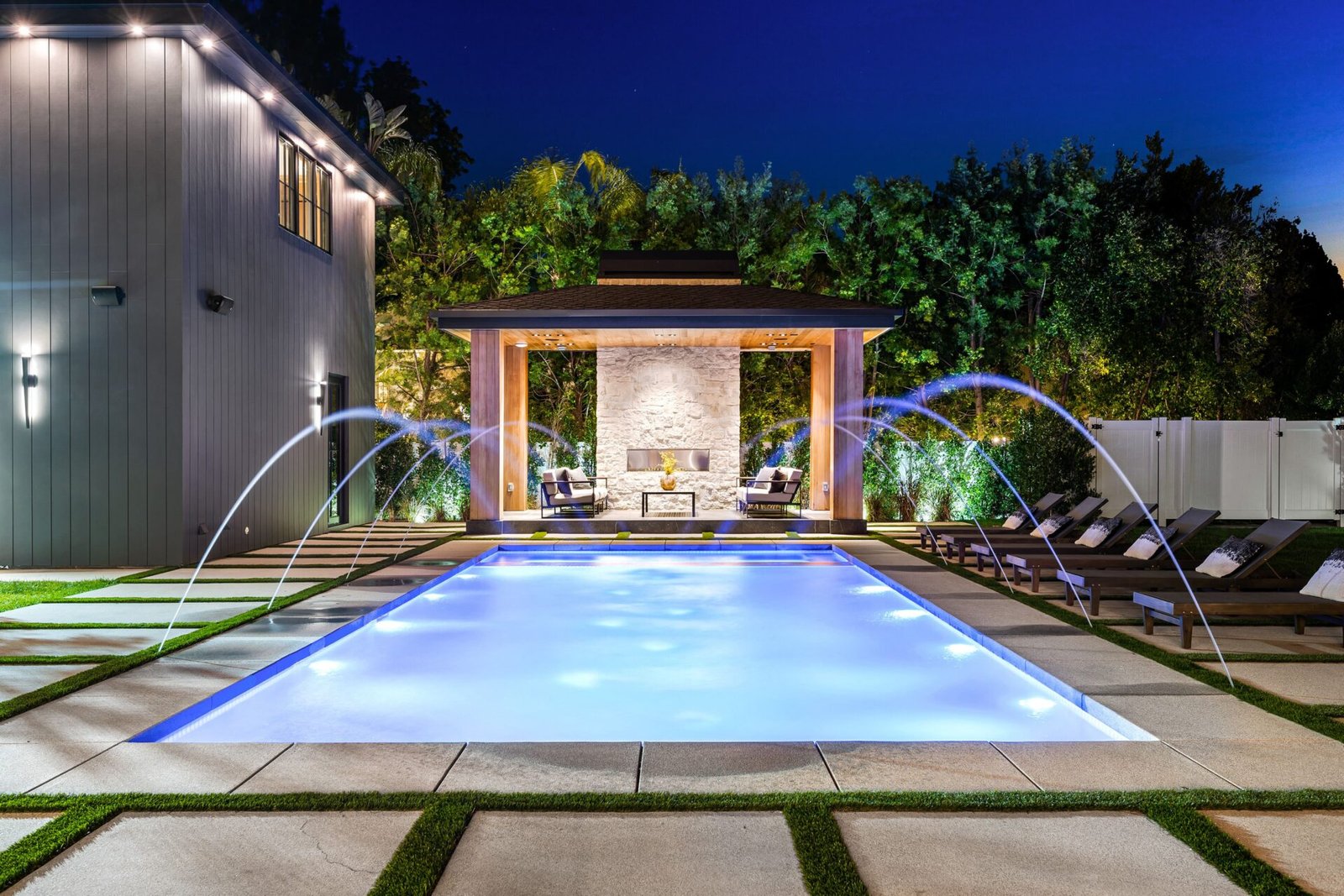 Luxurious modern backyard with illuminated swimming pool at night. in Fredericksburg